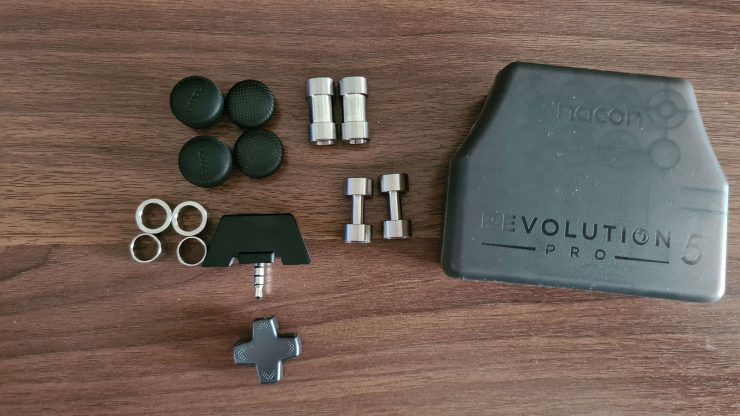 An image showing the carry case and accessories for the Nacon 5 Revolution pro including weights, changeable D-pad, and thumbsticks